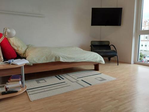 um quarto com uma cama, uma televisão e uma cadeira em Schloßtheater Ecostay em Münster