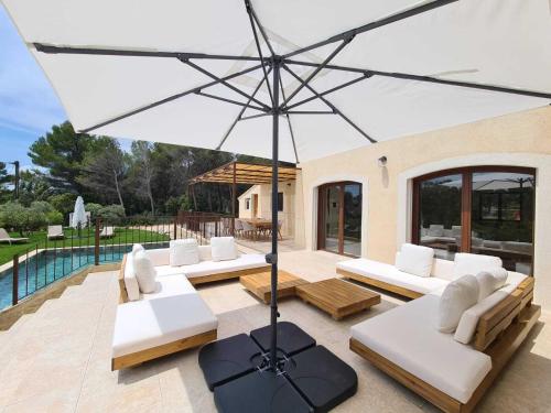 une terrasse avec des canapés blancs et un parasol dans l'établissement Villa de luxe en Luberon - Piscine chauffée, à Puget