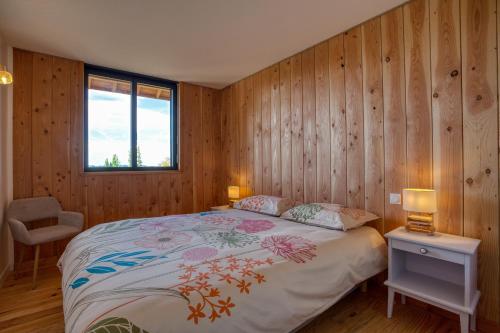 une chambre avec un lit avec des murs en bois et une fenêtre dans l'établissement Le Jardin de Lyno, à Belvès