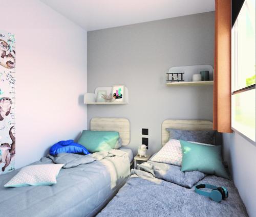 カステッレット・ソプラ・ティチーノにあるCamping Lido Verbanoの青と緑の枕が備わる客室内のベッド2台