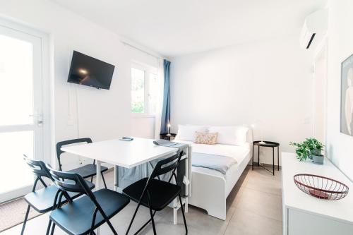 un soggiorno con divano bianco, tavolo e sedie di Le Betulle Studios by Quokka 360 - studio apartments by the Origlio lake a Origlio