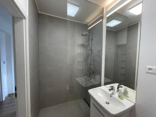 y baño blanco con lavabo y ducha. en New Stylish City Center Apartment, en Komárno