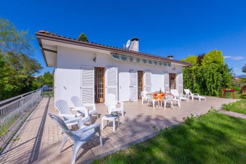 eine Terrasse mit weißen Stühlen und einem Tisch in der Unterkunft Villa Martine Au Bord Du Lac - Happy Rentals in Cadrezzate
