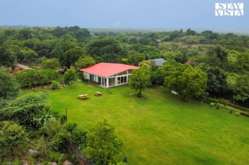 an aerial view of a house on a large green field at StayVista at Idyllic Farmhouse - A Glasshouse with Outdoor Pool in Gurgaon