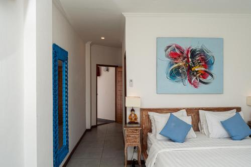 a bedroom with a bed and a painting on the wall at Komodo Suites Downtown in Labuan Bajo