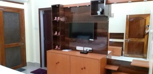 a living room with a flat screen tv on a dresser at Drizzle Homestay in Guwahati