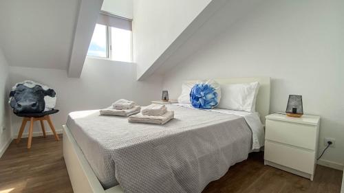 a white bedroom with a bed with towels on it at São Miguel Charming House by LFC Apts in Ponta Delgada