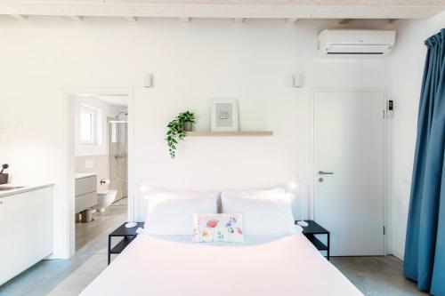 a white bedroom with a bed and blue curtains at Le Betulle Studios by Quokka 360 - studio apartments by the Origlio lake in Origlio