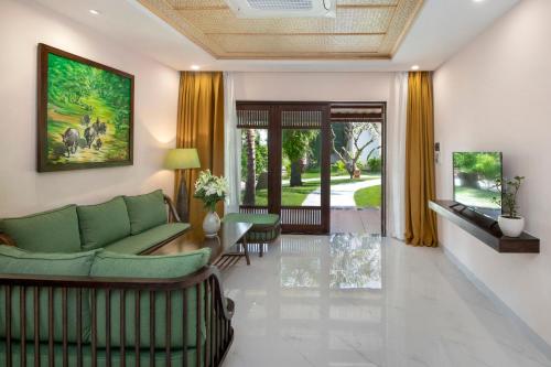 a living room with a green couch and chairs at Palm Garden Beach Resort & Spa in Hoi An