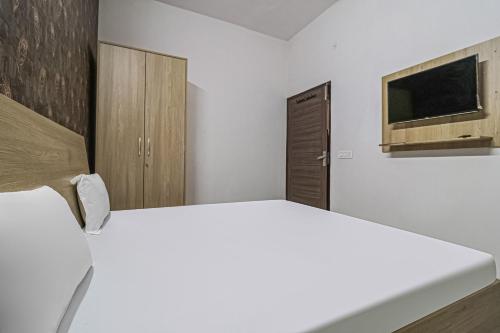 a white bedroom with a bed and a tv at OYO Prime Property in Ludhiana