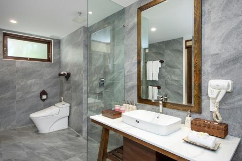 a bathroom with a sink and a toilet and a mirror at Palm Garden Beach Resort & Spa in Hoi An