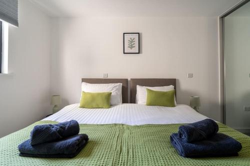 a bedroom with a bed with two blue pillows on it at The Zenith: Your Urban Oasis in Leicester
