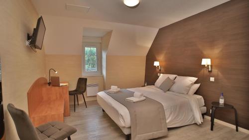 a hotel room with a large bed and a desk at L'HÔTEL DES BAINS - Salles-la-Source in Salles-la-Source