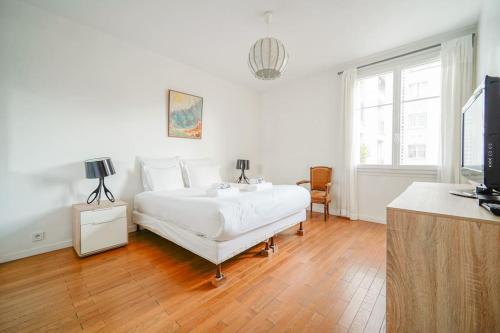 a white bedroom with a bed and a television at Appartement spacieux 17ème arrondissement - II in Paris