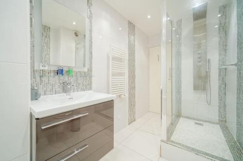 a white bathroom with a sink and a shower at Appartement spacieux 17ème arrondissement - II in Paris