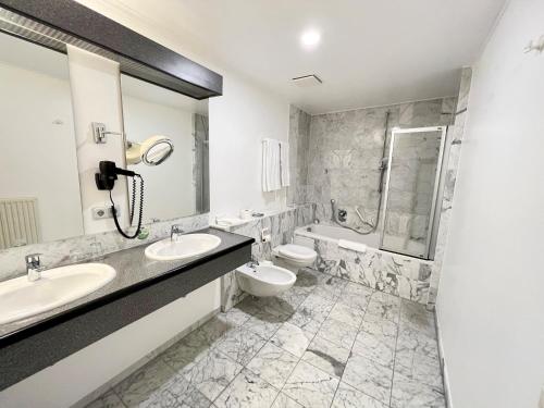 a bathroom with two sinks and a toilet and a shower at Hotel Residenz in Bad Neustadt an der Saale