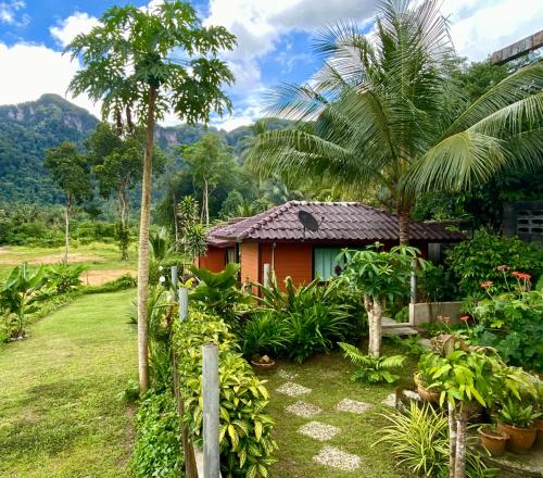 a small house in a garden with palm trees at Guesthouse 88 Phang Nga in Phangnga