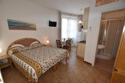 a bedroom with a bed and a kitchen and a table at Appartamenti Olivo - 100 mt dal mare con aria condizionata in Marina di Campo