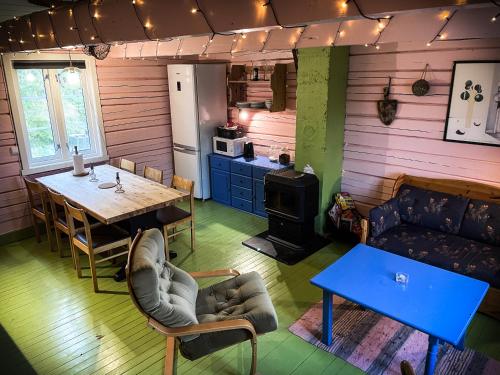 a living room with a table and a kitchen at Kræmmervika Rorbuer - Rustic Cabins & Hostel in Lofoten in Ballstad