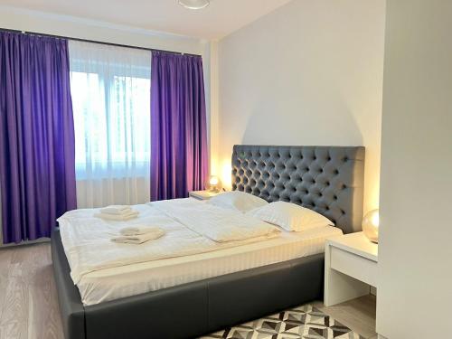 een slaapkamer met een groot bed met paarse gordijnen bij Central cozy Apartment in Cluj-Napoca