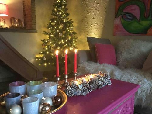 a living room with a christmas tree and candles on a table at La Petite maison in Montleban