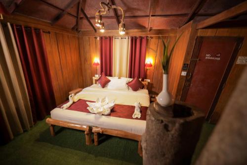 a bedroom with a large bed with red curtains at Nature Zone Jungle Resort in Munnar