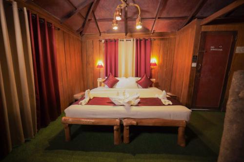 a bedroom with a large bed with red curtains at Nature Zone Jungle Resort in Munnar