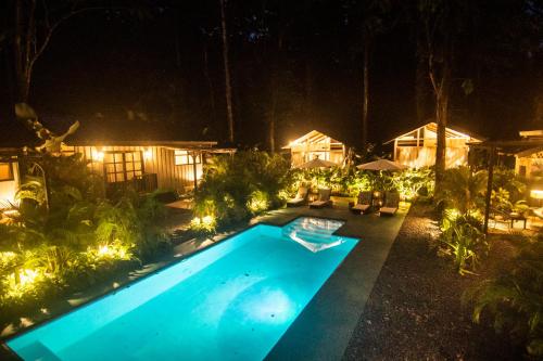 a swimming pool with lights in a yard at night at KAÑIK APART HOTEL in Puerto Viejo