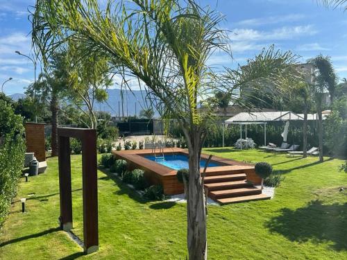 a garden with a swimming pool and a palm tree at Home Olympus Vesuvio in Pompei