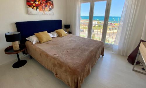 a bedroom with a large bed with a view of the ocean at Bleu Mer Duplex & Suites in Saint-Cyprien