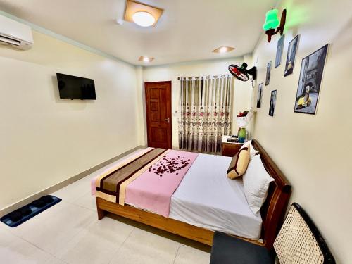 Manh Vuong Hotel في كات با: غرفة نوم مع سرير وتلفزيون على الحائط