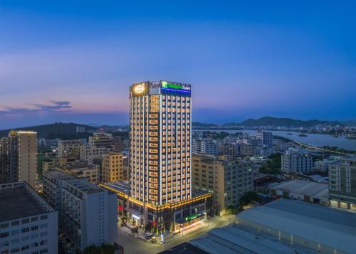 a tall building with lights on it in a city at Holiday Inn Express Shantou Chenghai in Shantou
