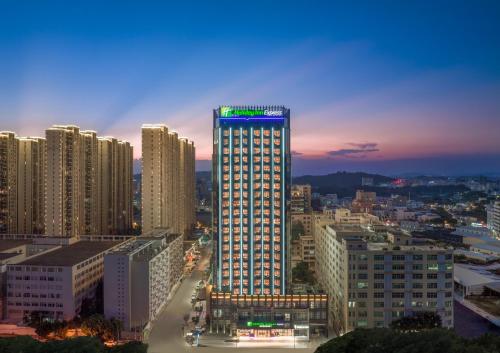 Holiday Inn Express Shantou Chenghai في شانتو: مبنى مضاء في مدينة في الليل