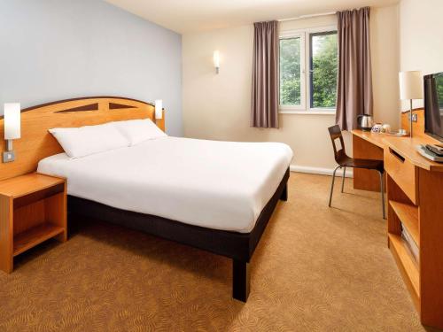 プレストンにあるイビス プレストン ノースのベッドとデスクが備わるホテルルームです。