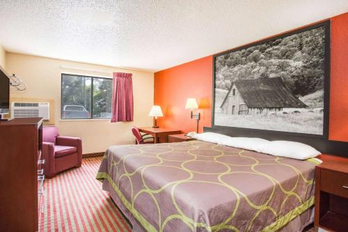 a hotel room with a bed and a large painting on the wall at Super 8 by Wyndham Harrisonburg in Harrisonburg