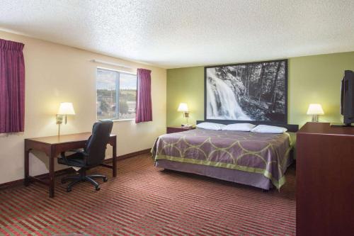 a hotel room with a bed and a desk and a computer at Super 8 by Wyndham Harrisonburg in Harrisonburg