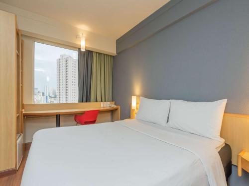 una camera d'albergo con letto, scrivania e finestra di ibis Guarulhos Aeroporto a Guarulhos