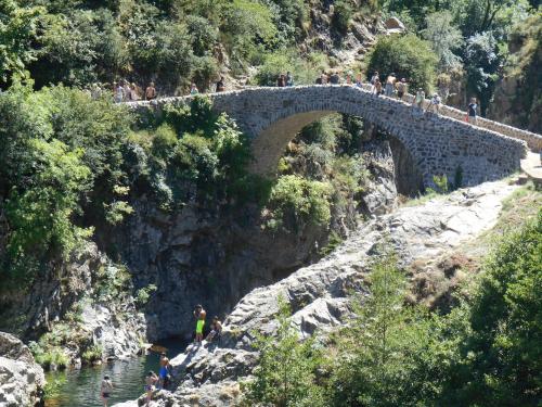a group of people crossing a stone bridge over a river at Hôtel La Gravenne in Thueyts