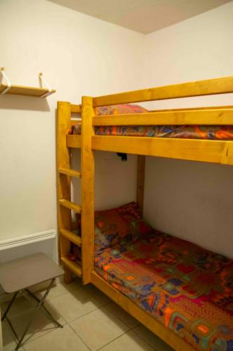 Un dormitorio con dos literas y una silla. en L'orée des pistes à Briançon, en Briançon