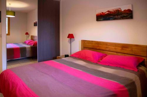 - une chambre avec un grand lit et des draps roses dans l'établissement L'orée des pistes à Briançon, à Briançon