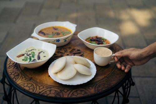 a table with bowls and plates of food on it at La Cascade Resort in Athirappilly