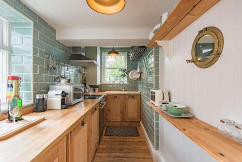 a kitchen with wooden counters and green tiles at SeaFern Cottage in Whitstable