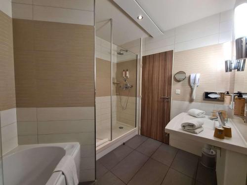 La salle de bains est pourvue d'une baignoire, d'une douche et d'un lavabo. dans l'établissement Mercure Libourne Saint Emilion, à Libourne