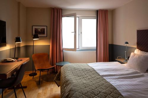 a hotel room with a bed and a desk and a window at Best Western Plus Hotel Noble House in Malmö