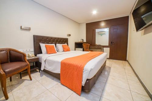 a bedroom with a large bed and a chair at Hotel Kalisma by Alia in Jakarta