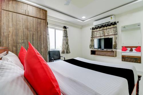 a bedroom with a large bed with red pillows at Super Capital O Vrisha Inn in Jalāripeta