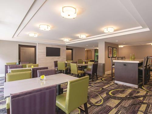 a hotel room with tables and chairs and a tv at La Quinta Inn & Suites by Wyndham Portland DT Maine Med in Portland