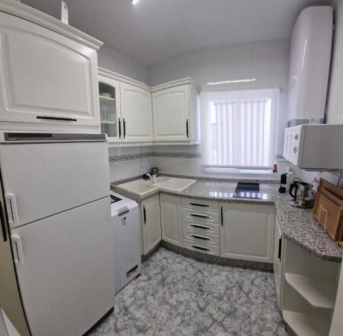 una cocina blanca con electrodomésticos blancos y armarios blancos en DS Luxury Center, en Córdoba