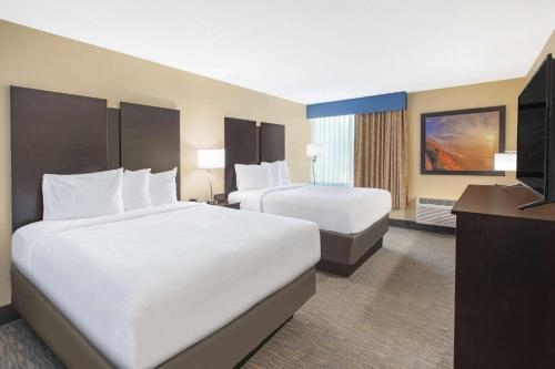 a hotel room with two beds and a television at Days Inn & Suites by Wyndham Grand Rapids Near Downtown in Grand Rapids