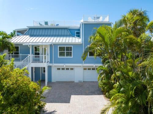 a blue house with palm trees in front of it at Murmond- Captiva Home in Captiva
